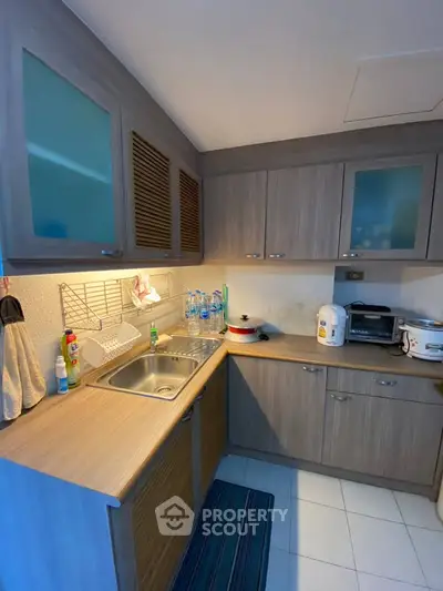 Modern kitchen with wooden cabinets and stainless steel sink in cozy apartment.