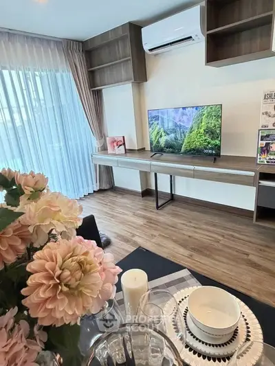 Modern living room with stylish decor, large window, and mounted TV in a cozy apartment.