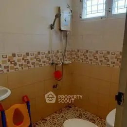 Compact bathroom with shower and child seat, tiled walls and floor.