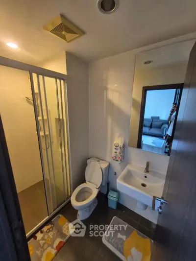 Modern bathroom with shower, toilet, and sink in a cozy apartment setting.