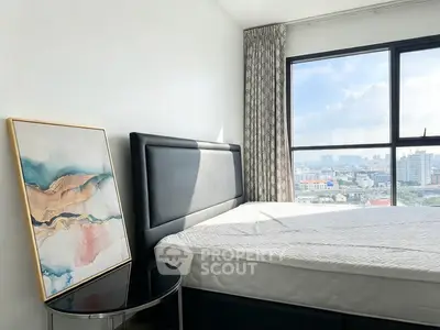 Modern bedroom with large window offering stunning city view and elegant decor.