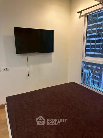 Cozy bedroom with wall-mounted TV and city view window