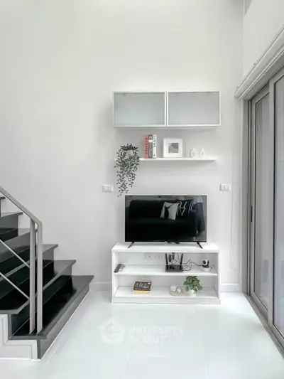 Modern living room with sleek TV stand and staircase, bright and minimalistic design.