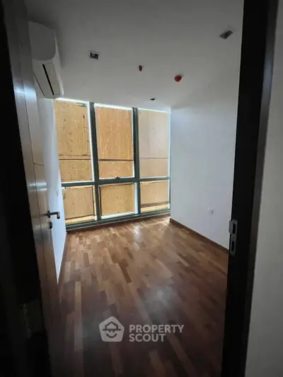 Spacious room with wooden flooring and large windows, perfect for natural light.