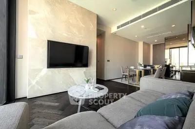 Modern living room with sleek design and open dining area, featuring a wall-mounted TV and stylish furniture.