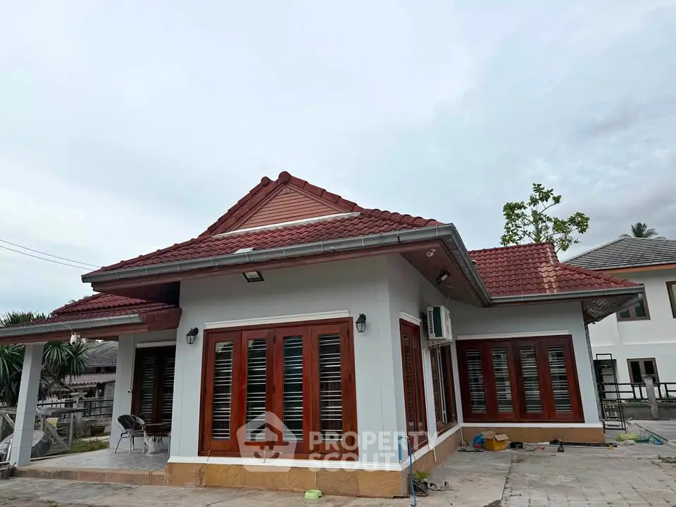 Charming single-story house with red roof and wooden accents, perfect for family living.