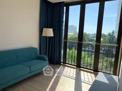 Bright living room with large windows and blue sofa, offering a scenic view.