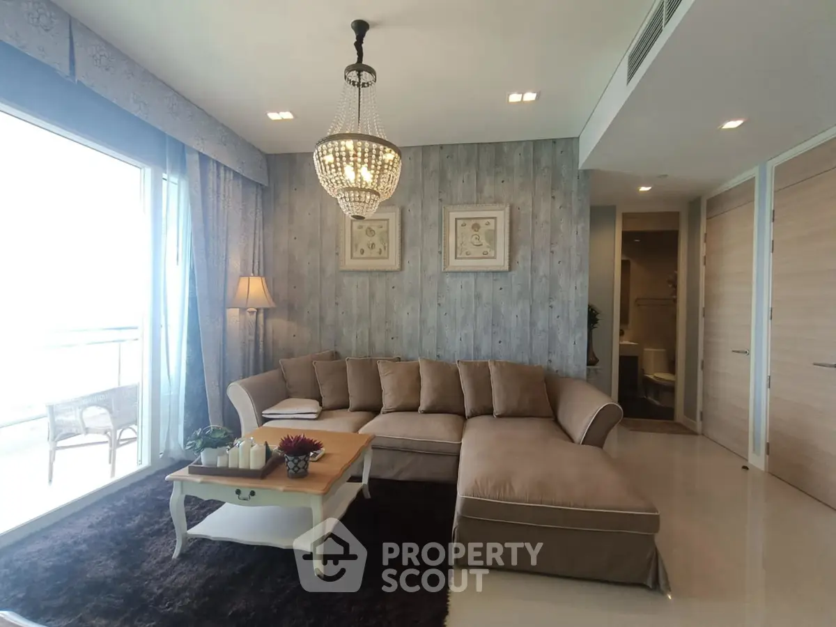 Elegant living room with plush sofa and chandelier, featuring a cozy ambiance and modern decor.