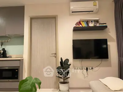 Modern living room with wall-mounted TV, air conditioning, and sleek kitchen appliances.