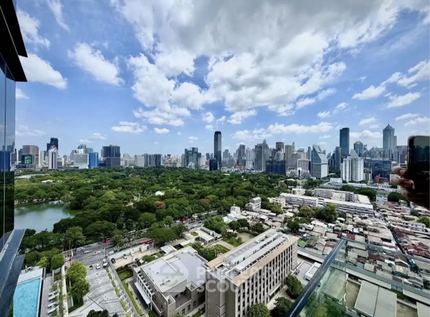 Stunning cityscape view from high-rise balcony overlooking lush park and skyline.