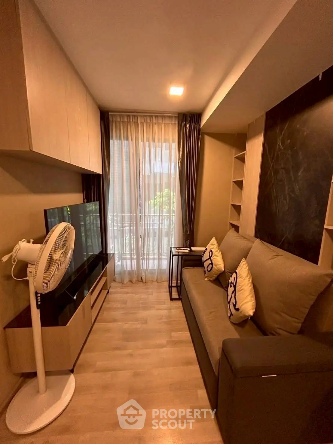 Cozy living room with modern decor and natural light, featuring a comfortable sofa and stylish shelving.