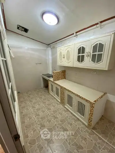 Charming kitchen with unique tile flooring and ample cabinet space, perfect for culinary enthusiasts.