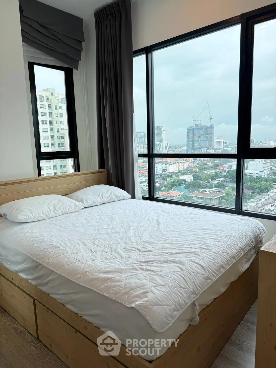 Modern bedroom with large windows offering stunning city views.