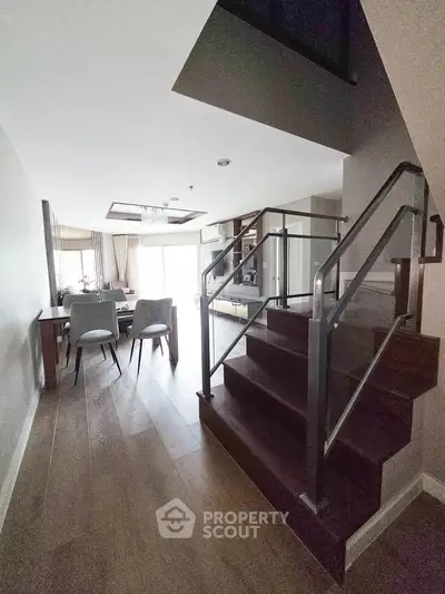 Modern duplex interior with stylish staircase and dining area, featuring elegant wooden flooring and contemporary decor.