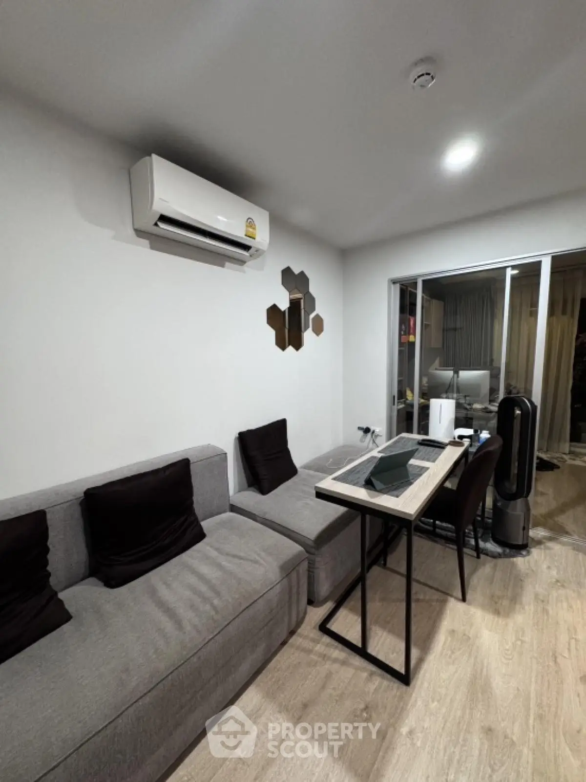 Modern living room with sleek furniture and air conditioning, featuring a cozy workspace.
