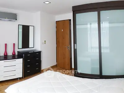 Modern bedroom with sleek furniture and frosted glass wardrobe