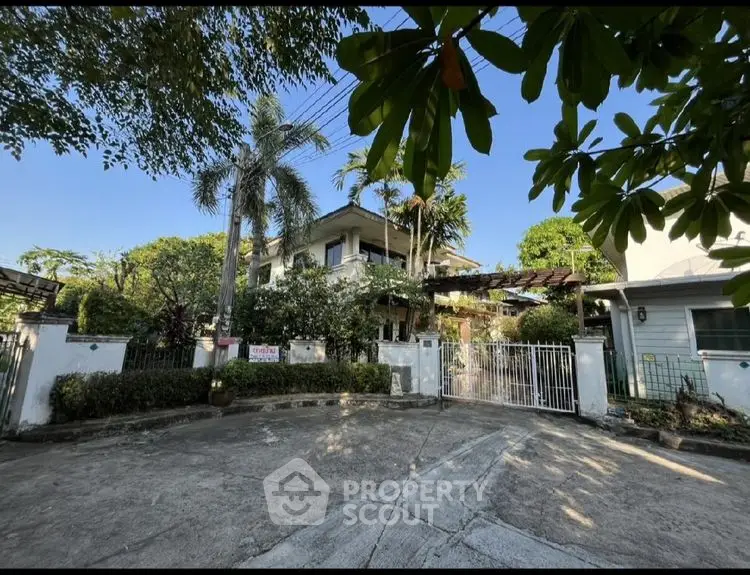 Charming two-story house with lush garden and gated entrance in serene neighborhood.