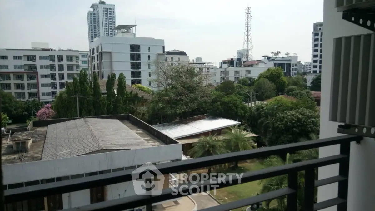 Stunning urban view from balcony overlooking lush greenery and modern buildings.