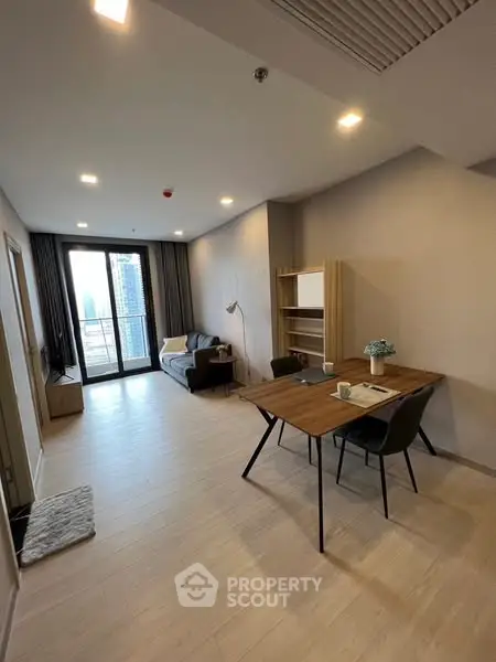 Modern living room with balcony view, stylish furniture, and ample natural light.