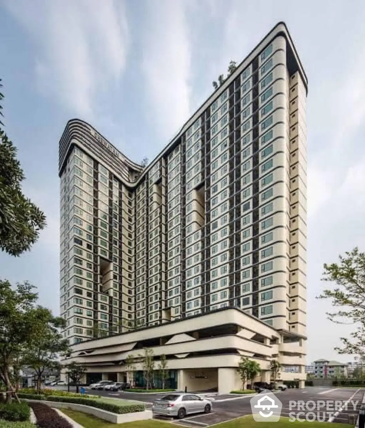 Modern high-rise residential building with unique architectural design and lush surroundings.