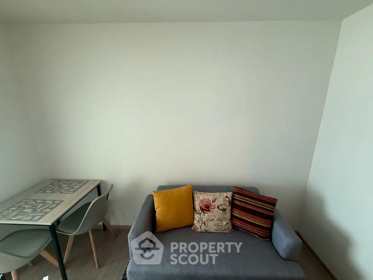 Cozy living room with modern sofa and dining table, perfect for small spaces.