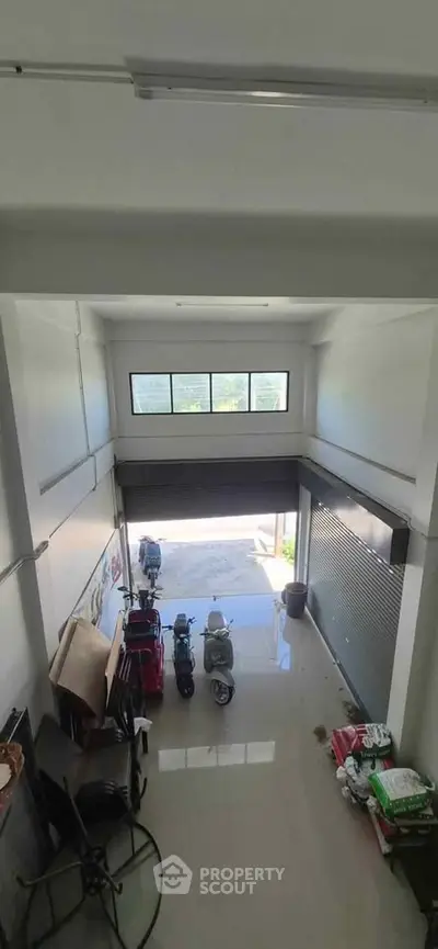Spacious commercial garage with high ceiling and large windows, ideal for business or storage use.