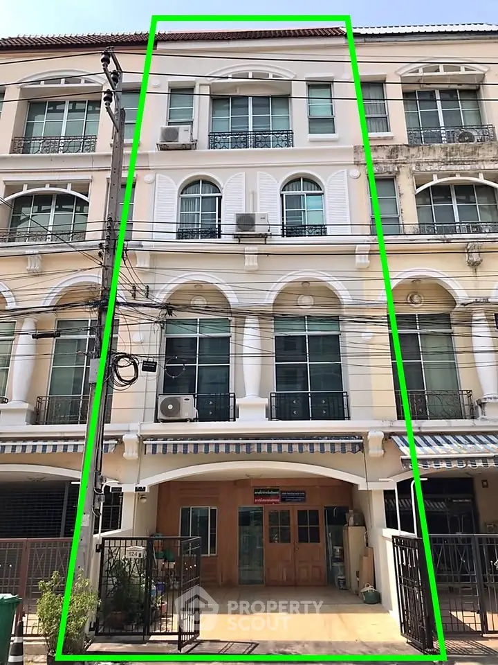 Charming multi-story townhouse with classic facade and balcony in urban setting.