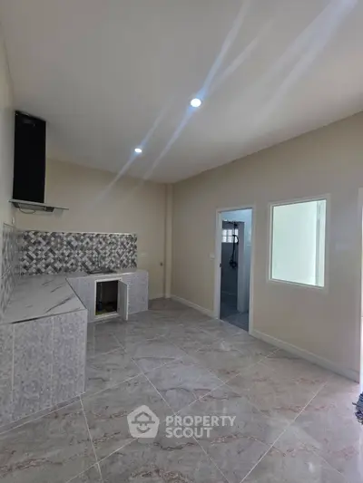 Modern kitchen with tiled backsplash and open layout, featuring sleek countertops and ample natural light.