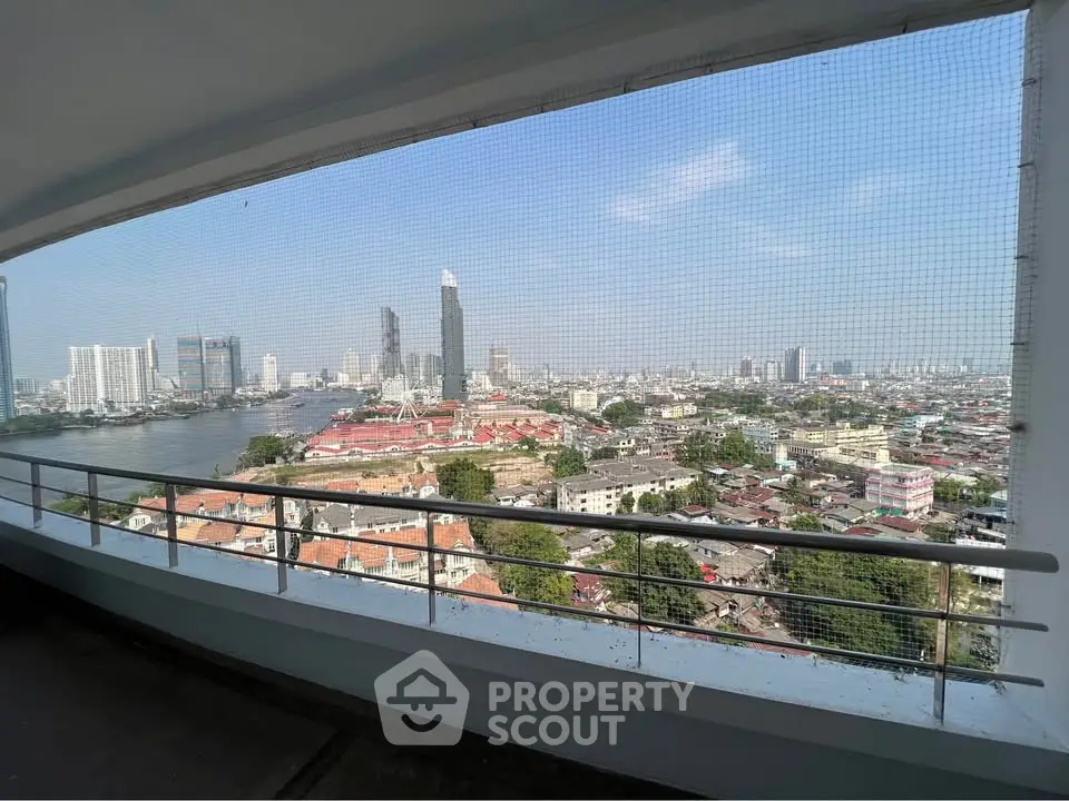 Stunning cityscape view from high-rise balcony overlooking river and skyline.