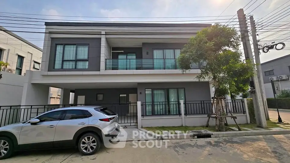 Modern two-story house with sleek design and spacious driveway in a suburban neighborhood.