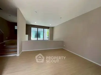 Spacious empty living room with wooden flooring and large window