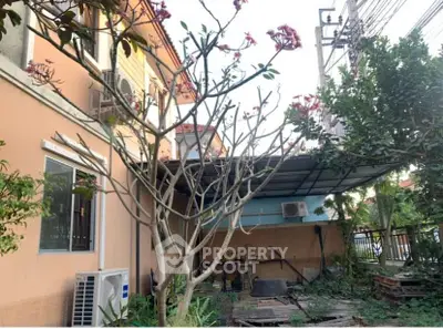 Charming residential exterior with lush garden and covered patio area.