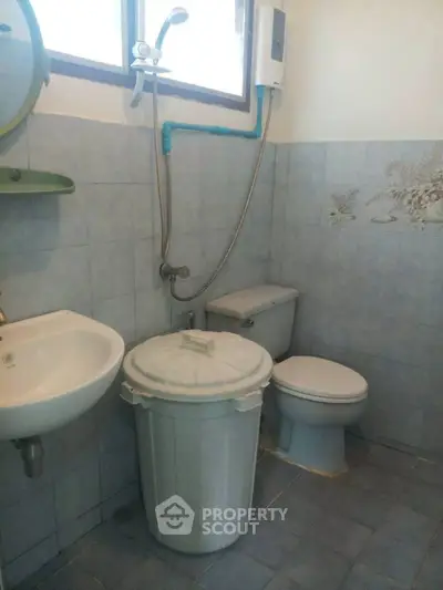 Compact bathroom with essential fixtures and tiled walls, featuring a shower, sink, and toilet.