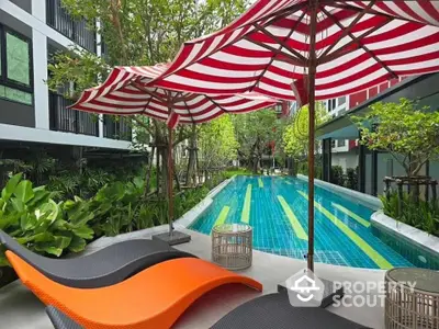 Luxurious poolside area with vibrant umbrellas and lush greenery in modern residential complex.