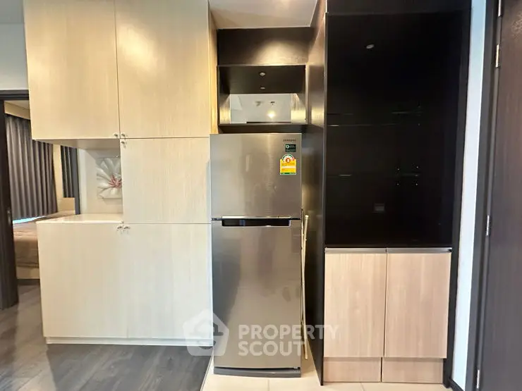 Modern kitchen with sleek cabinetry and stainless steel fridge in a stylish apartment.