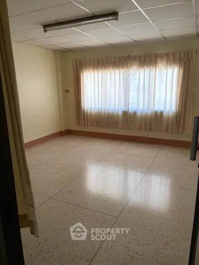 Spacious empty room with large window and tiled floor, ideal for customization.