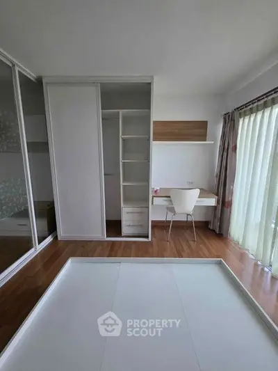 Modern bedroom with built-in wardrobe and study desk, featuring floor-to-ceiling windows for natural light.