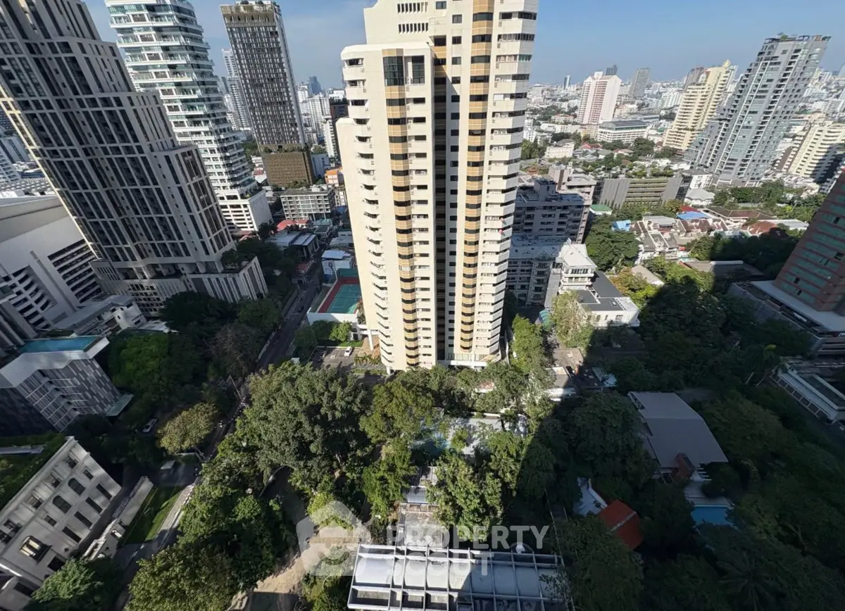 Stunning cityscape view from high-rise apartment overlooking urban skyline and lush greenery.