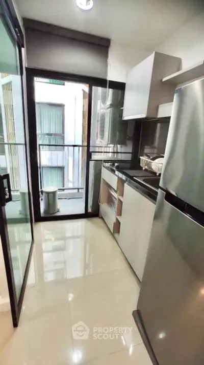 Modern kitchen with sleek appliances and balcony access in urban apartment