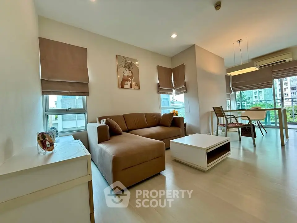 Spacious modern living room with cozy sofa and dining area, featuring large windows and stylish decor.