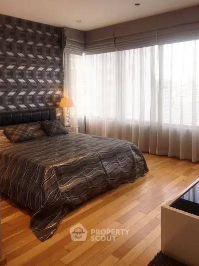 Luxurious bedroom with modern decor and large windows offering natural light.