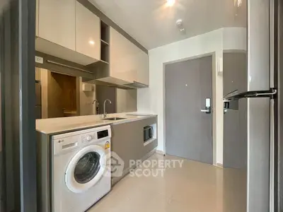 Modern kitchen with sleek appliances and washing machine in a compact layout.
