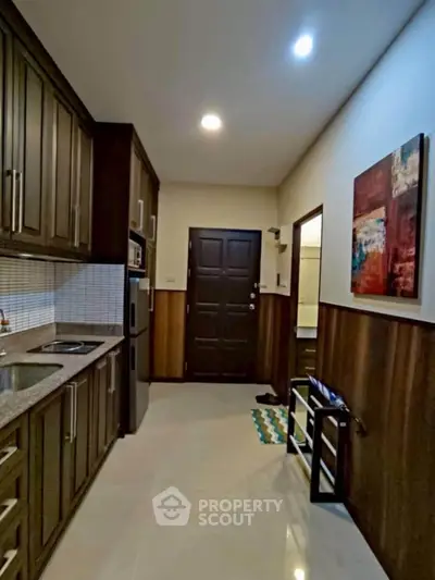 Modern kitchen with wooden cabinets and sleek countertops in a cozy apartment.