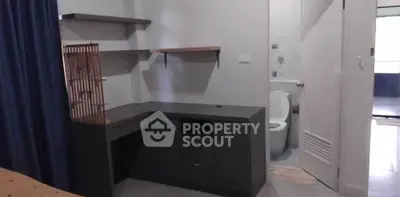 Cozy study nook with built-in desk and shelves next to a bathroom entrance.