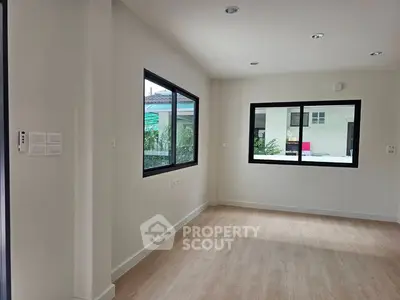 Spacious and bright room with large windows and wooden flooring, perfect for modern living.