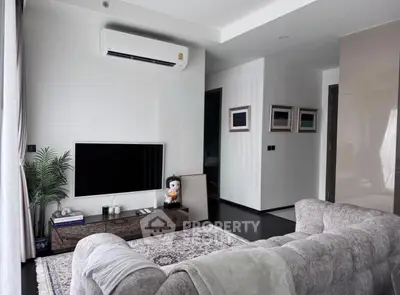 Modern living room with plush sofa, wall-mounted TV, and air conditioning in a stylish apartment.
