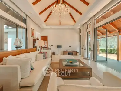 Luxurious living room with high ceilings, elegant chandelier, and large windows opening to a garden view.