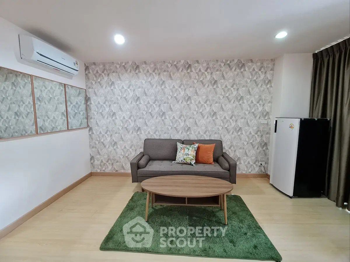 Modern living room with stylish sofa, air conditioning, and chic wallpaper.