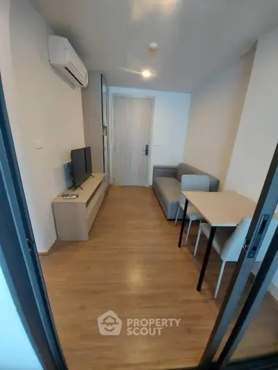 Modern compact living room with sleek furniture and wooden flooring in a cozy apartment.