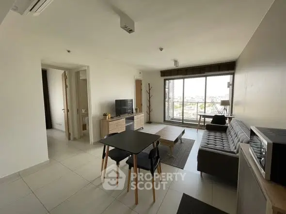 Modern living room with stylish furniture and large window offering city views.